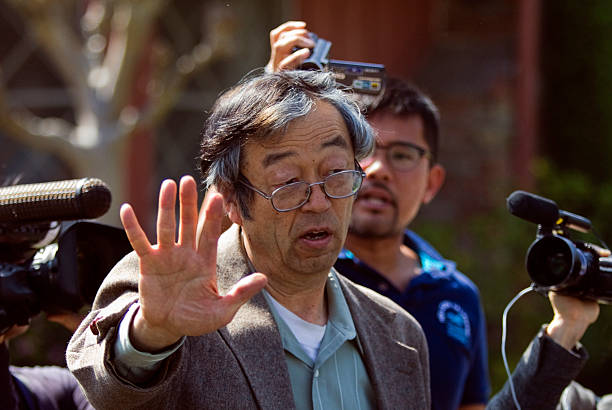 Satoshi Nakamoto raises his hand in front of camera